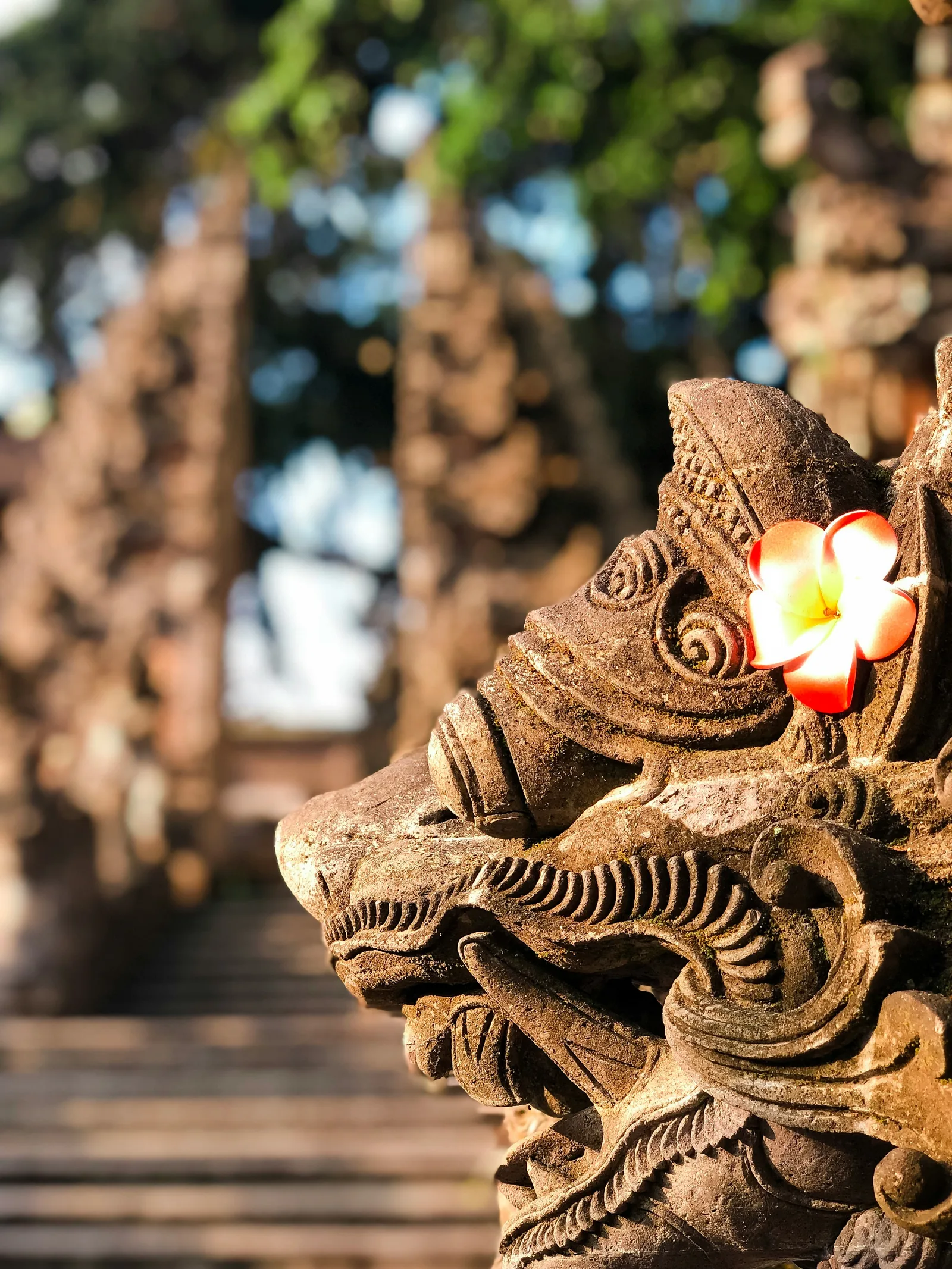 Balinese stone statue surrounded by greenery and soft light